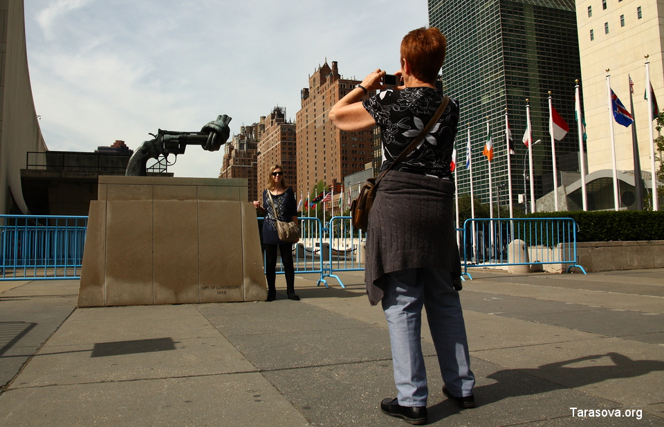 Туристы  фотографируются на фоне скульптуры